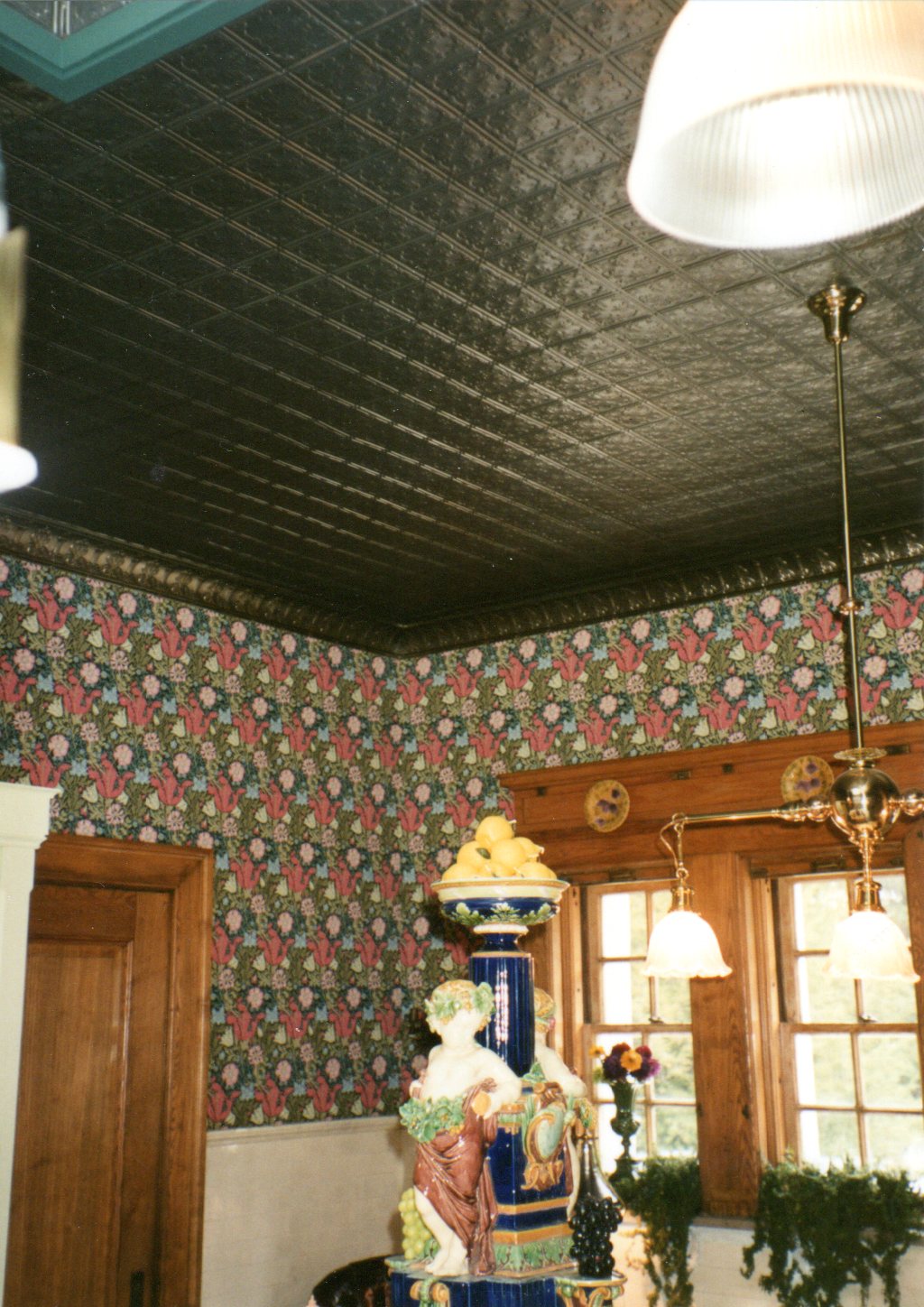 Decorative interior with floral wallpaper, a large figurine, and hanging lights.