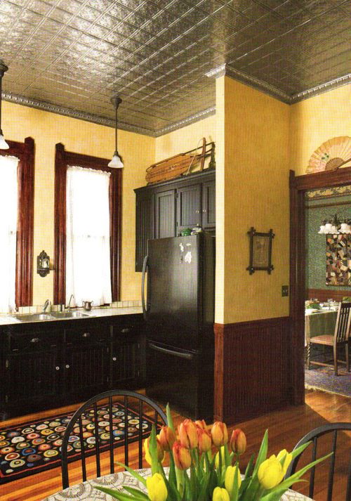 Vintage-style kitchen with dark wood cabinets, a refrigerator, and decorative ceiling.