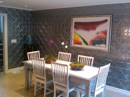 Dining area with a table and chairs against a textured wall with a colorful painting.
