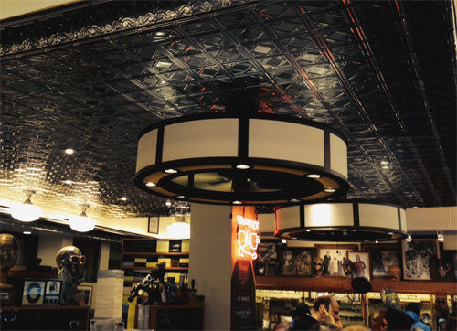 Ceiling light fixture in a bar with decorative ceiling and patrons in the background.
