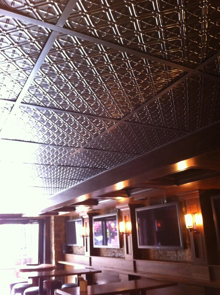 Ceiling with decorative pattern and wall-mounted televisions in a room setting