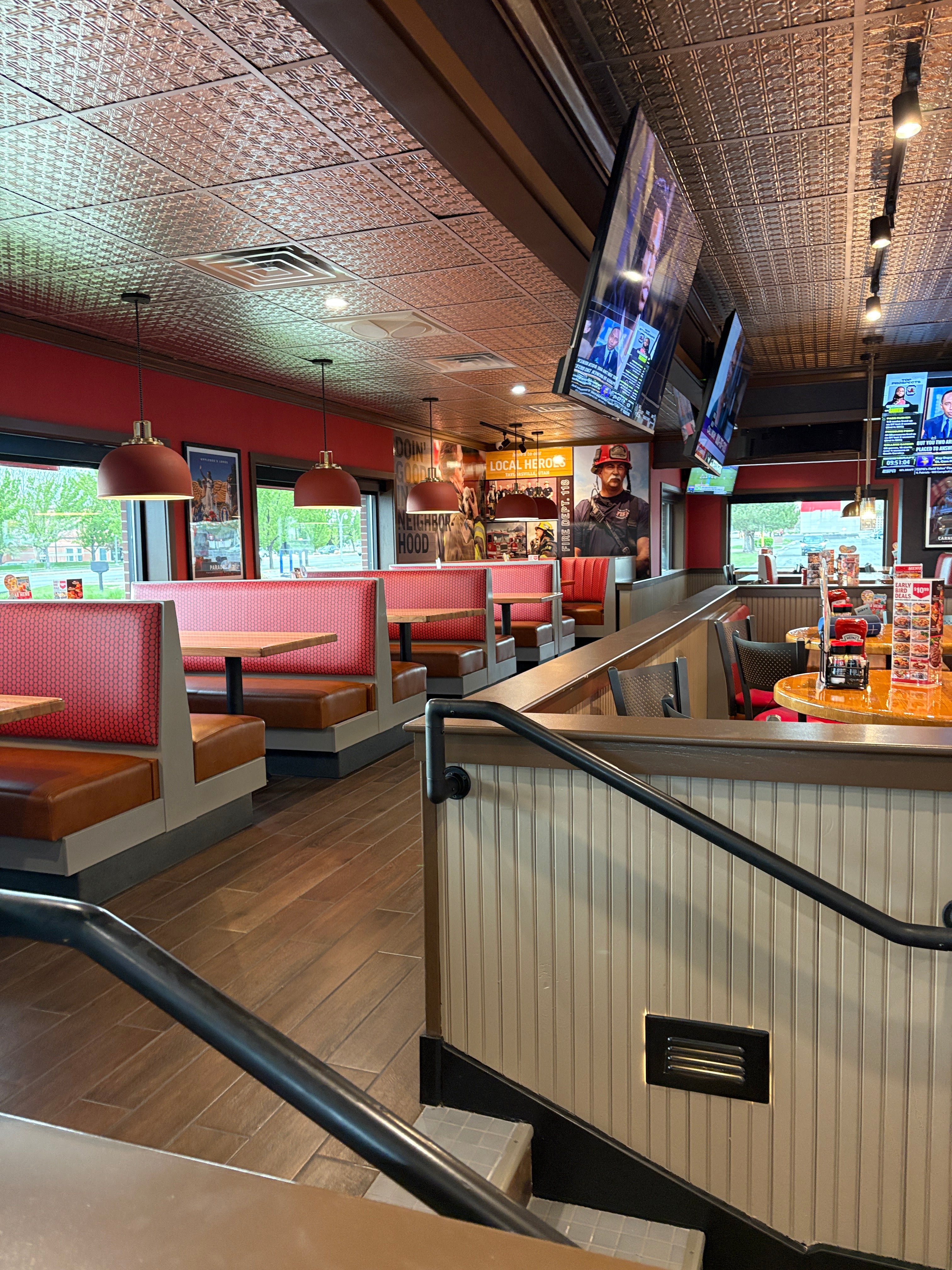 Interior of a restaurant with tiled walls, counter, and staircase.
