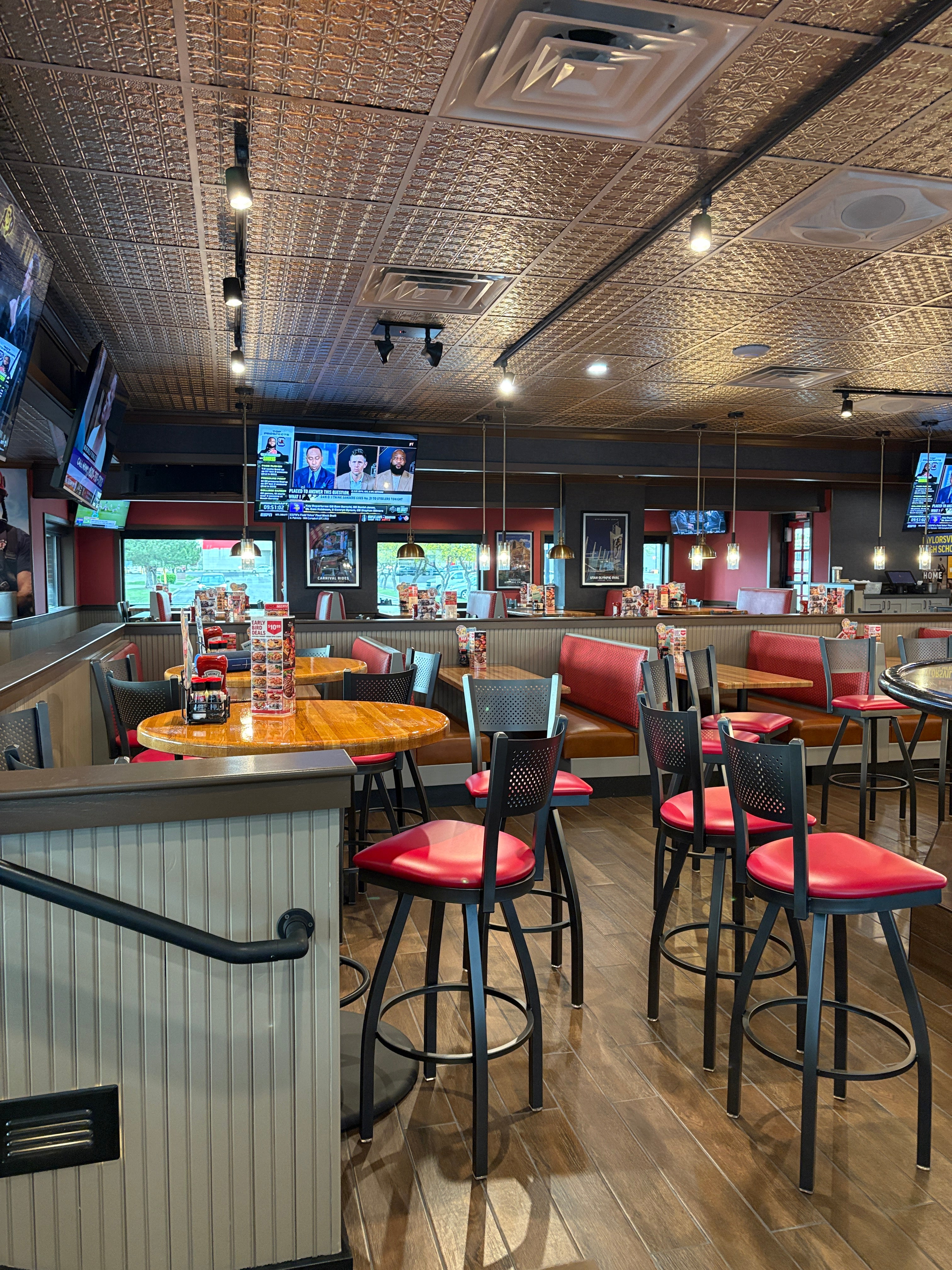 Restaurant interior with tables, chairs, and televisions on the wall.