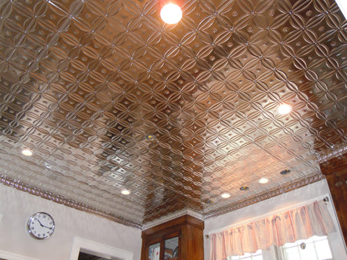 Ceiling with decorative tin tiles in a room with a clock and window.