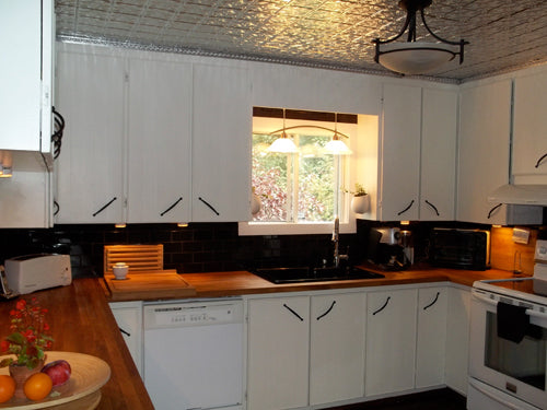 Modern kitchen with white cabinets, black backsplash, and stainless steel appliances.