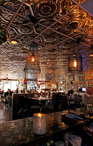 Interior of a bar with ornate ceiling and patrons seated at tables.