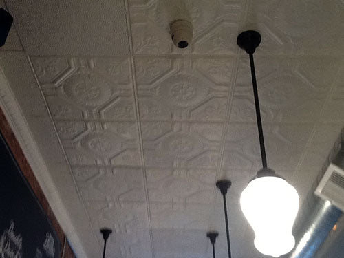 Light bulb hanging from a ceiling with decorative tiles