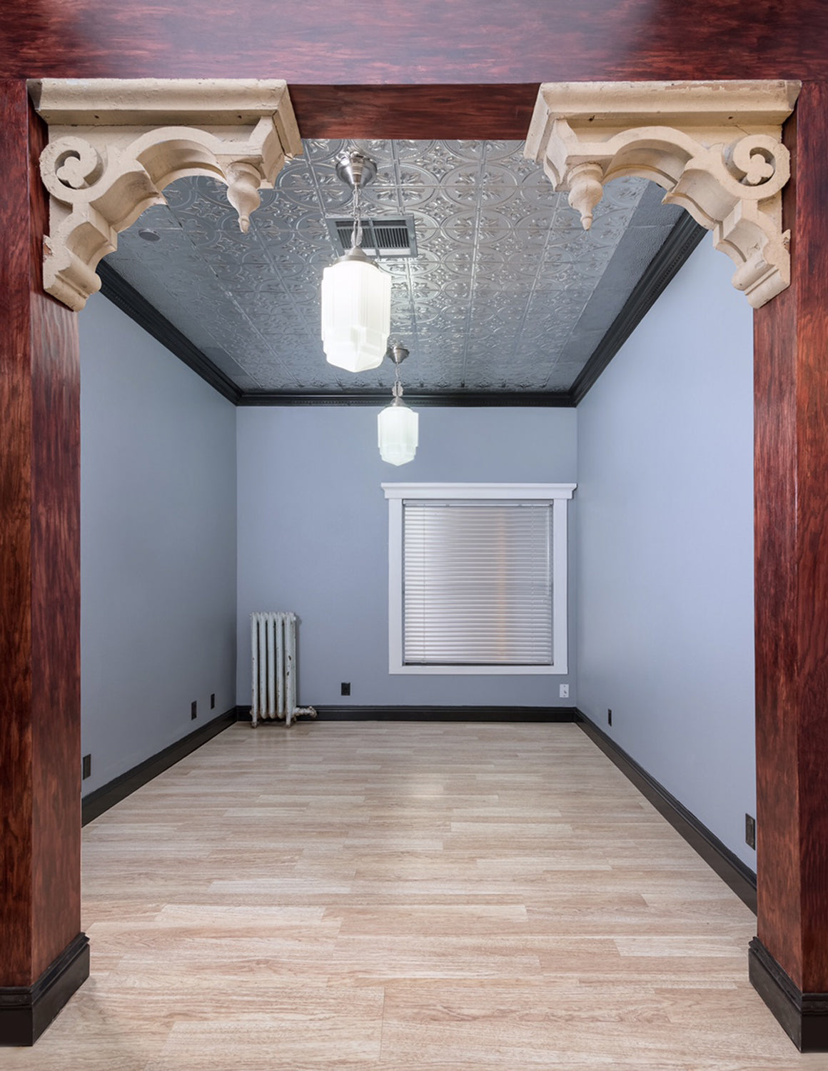 Empty room with decorative archway, light blue walls, wooden floor, and white ceiling.