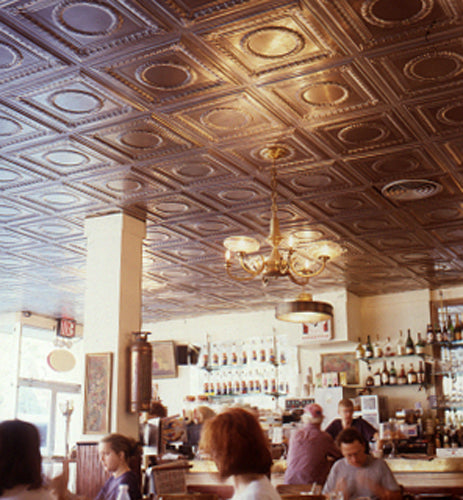 Interior of a bar with ornate ceiling tiles and patrons seated at tables.