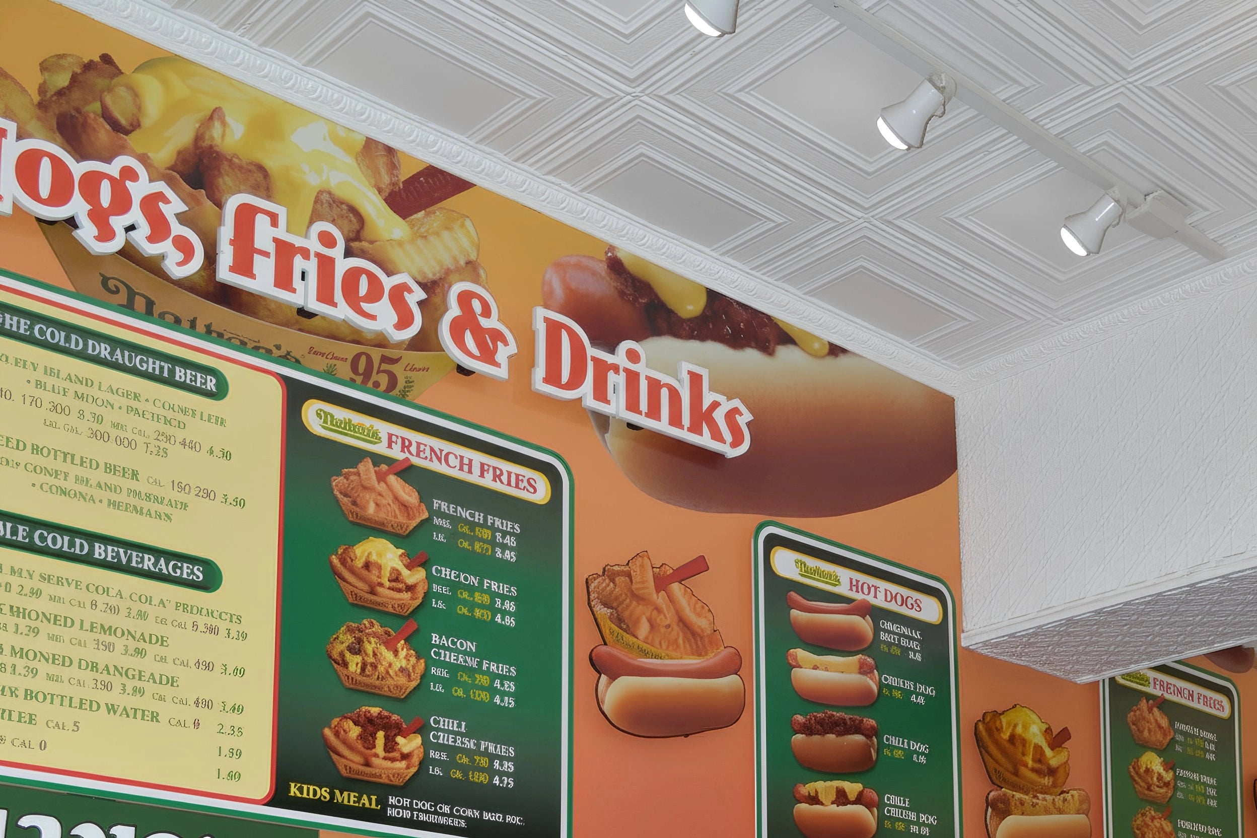 Menu board with food items and prices on a wall, featuring a hot dog and fries illustration.