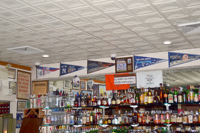 Alcohol bottles on shelves with sports team banners on the wall above.
