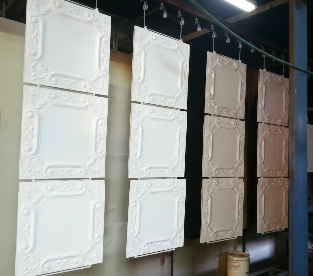 Decorative ceiling panels hanging on a rack in an industrial setting