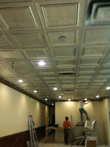 Ceiling with square tiles and people working on a renovation project.