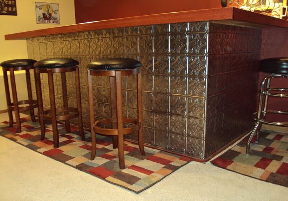 Bar area with tiled wall and bar stools in a room with a patterned rug.