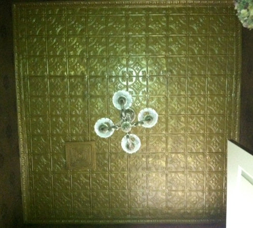 Chandelier hanging from a textured green ceiling.