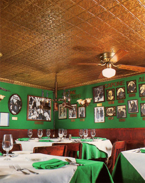 Dining room with green walls, white tables, and decorative ceiling.