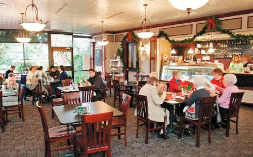 Dining area with tables and chairs, people seated, and a festive atmosphere.