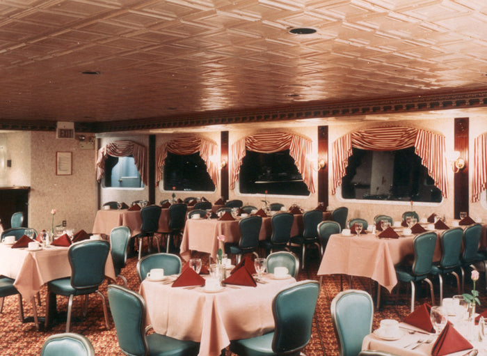 Dining hall with tables, chairs, and decorative drapes.