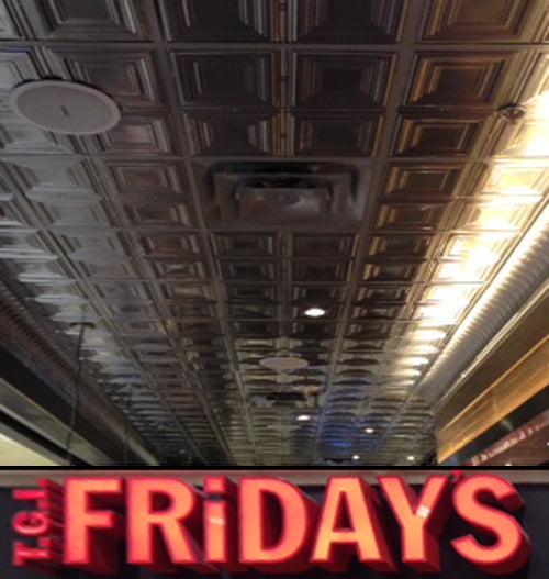 Red 'TGI Fridays' sign on a ceiling with decorative tiles