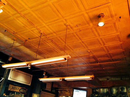 Ceiling with tiled design and hanging lights in a dimly lit room.