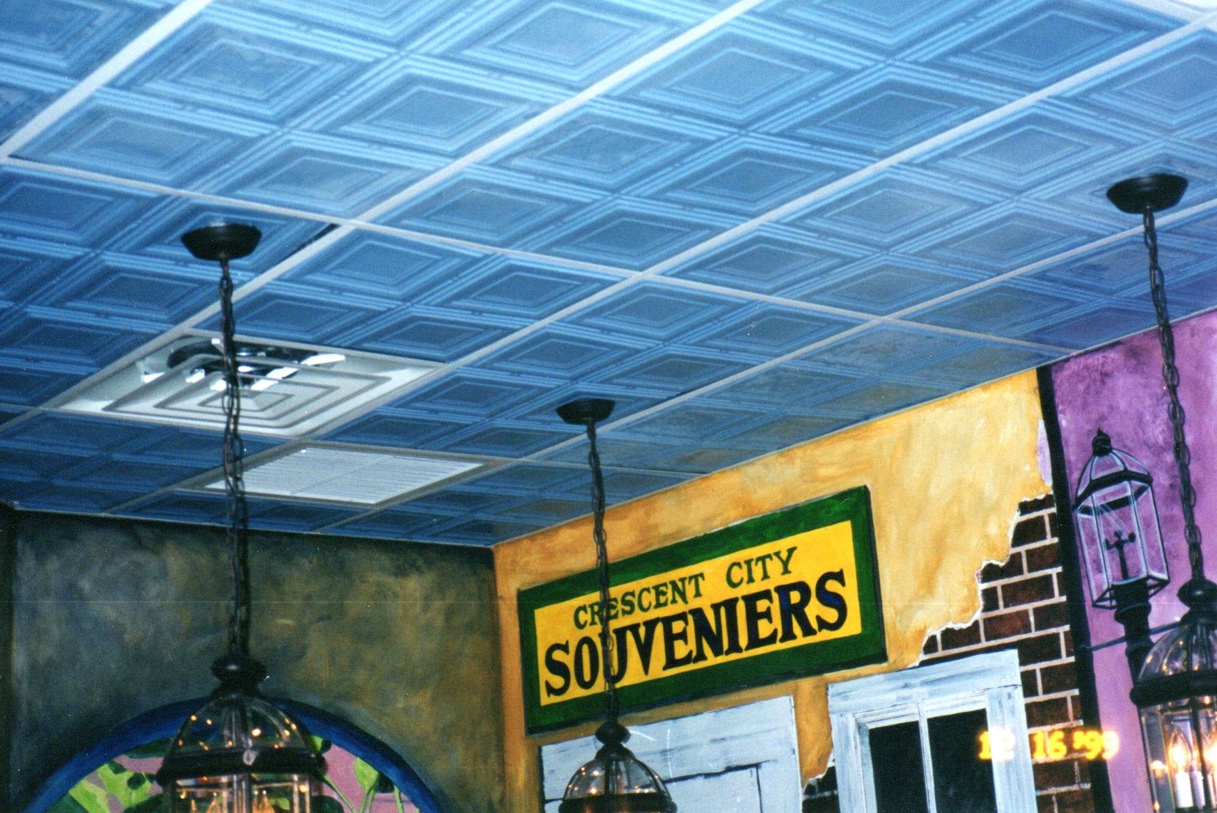Ceiling with decorative tiles and a sign reading 'Crescent City Souvenirs'.