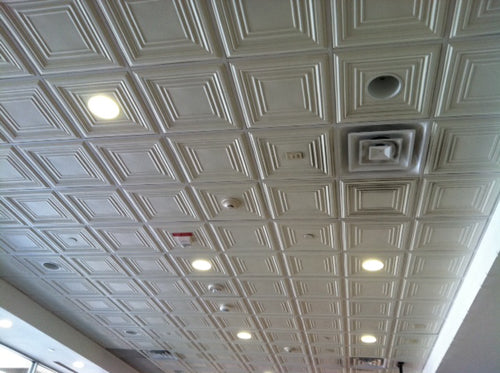 Ceiling with a tiled design featuring lights and a fire alarm.