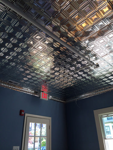 Ceiling with decorative square pattern and blue walls with a fire exit sign.