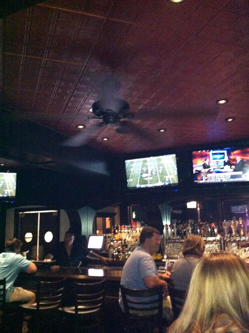 Bar interior with patrons and multiple televisions displaying sports content.