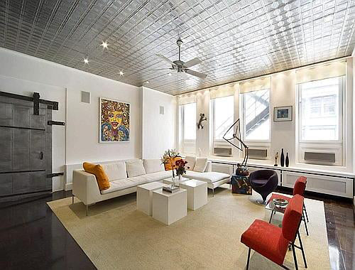 Modern living room with white sofa, red chairs, and decorative items.