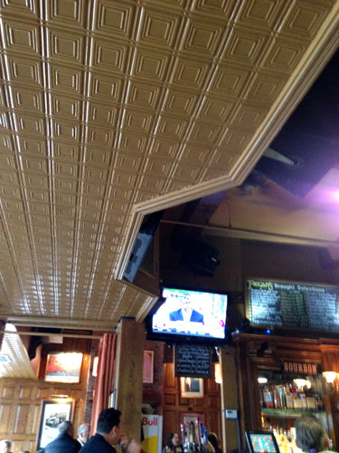 Bar interior with tiled ceiling and television screens.