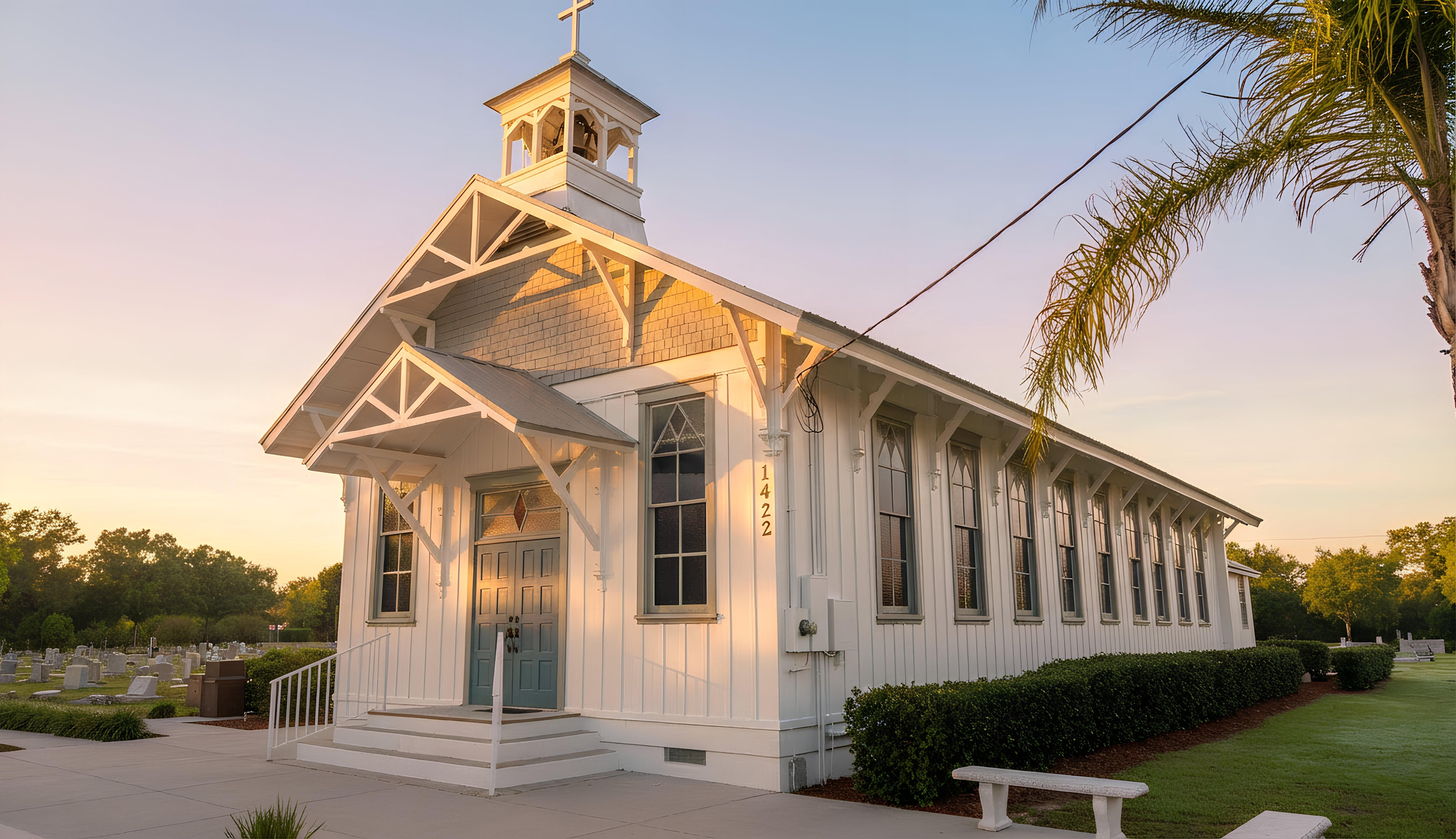 Small white church with a bell tower at sunset.