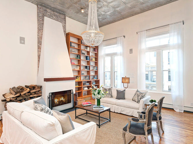 Living room with white sofas, a fireplace, bookshelf, and decorative items.