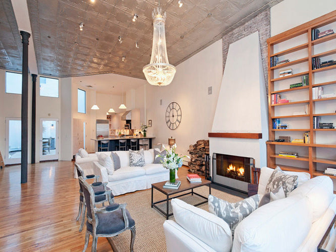 Modern living room with white sofas, a fireplace, and bookshelves.