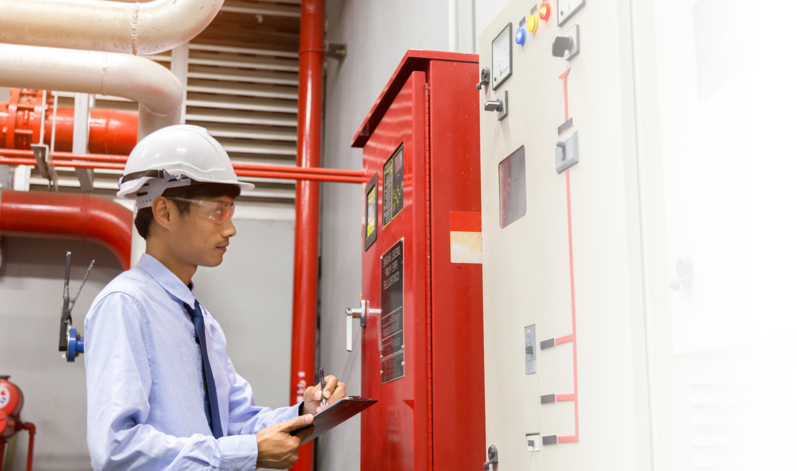 Person in a hard hat inspecting equipment in an industrial setting.