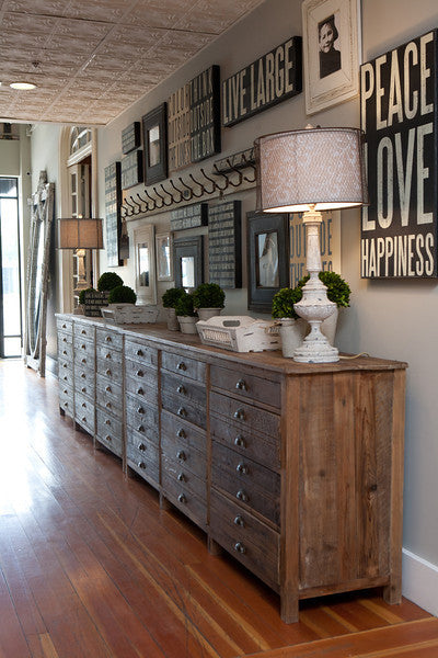 Long wooden dresser with decorative items in a room with framed art on the wall.