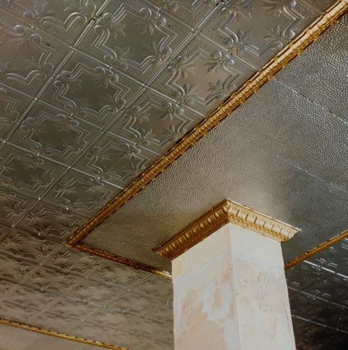 Decorative ceiling with embossed pattern and gold trim, featuring a column.