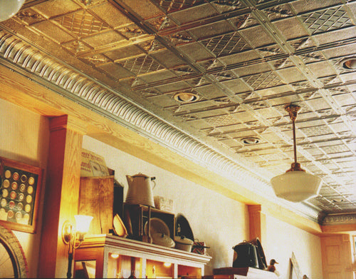 Ceiling with decorative tiles and a room with furniture and decor.