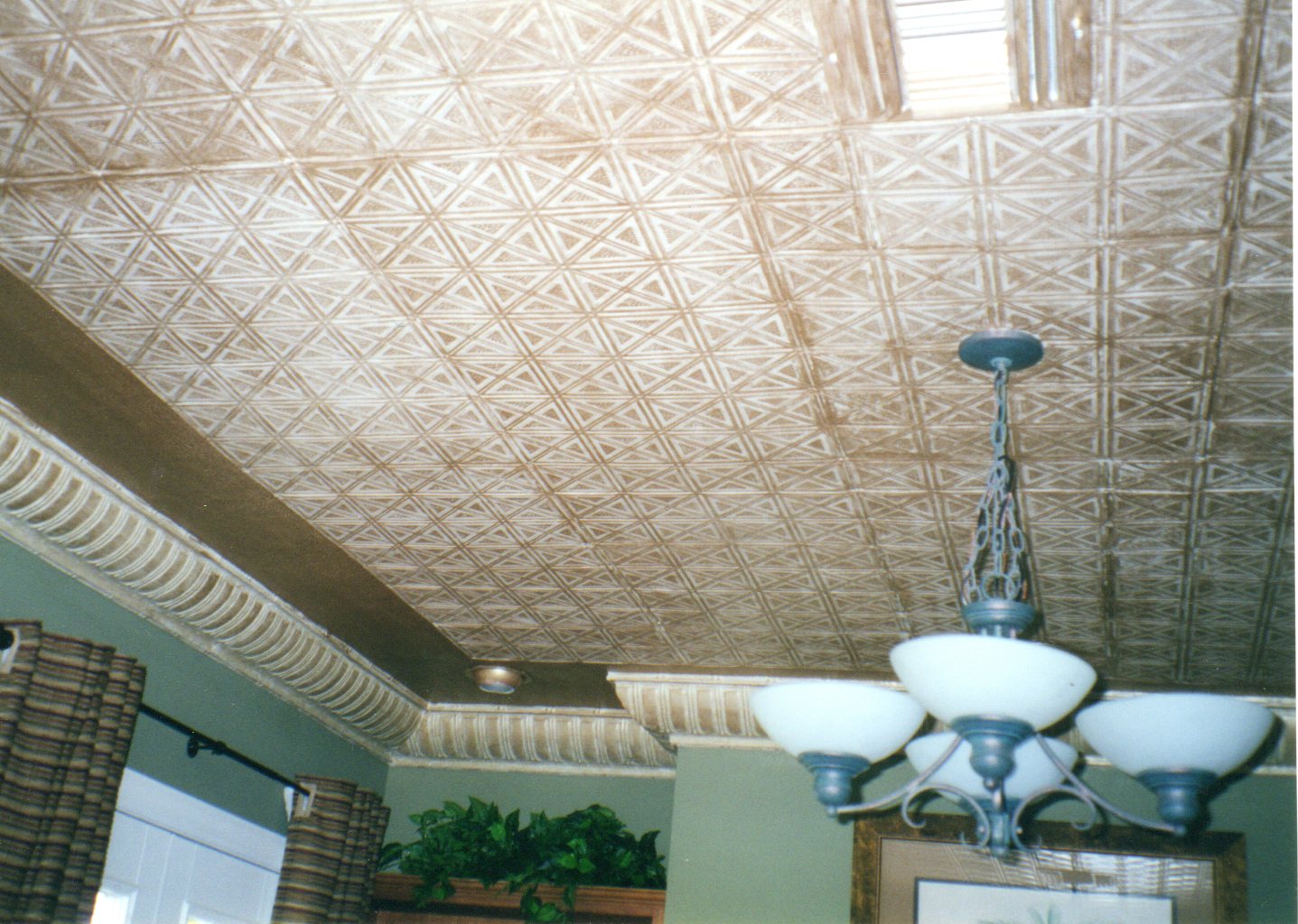 Decorative ceiling with geometric pattern and a chandelier in a room.