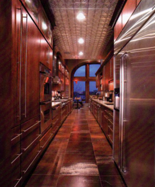 Long narrow kitchen with wooden cabinets and stainless steel appliances.