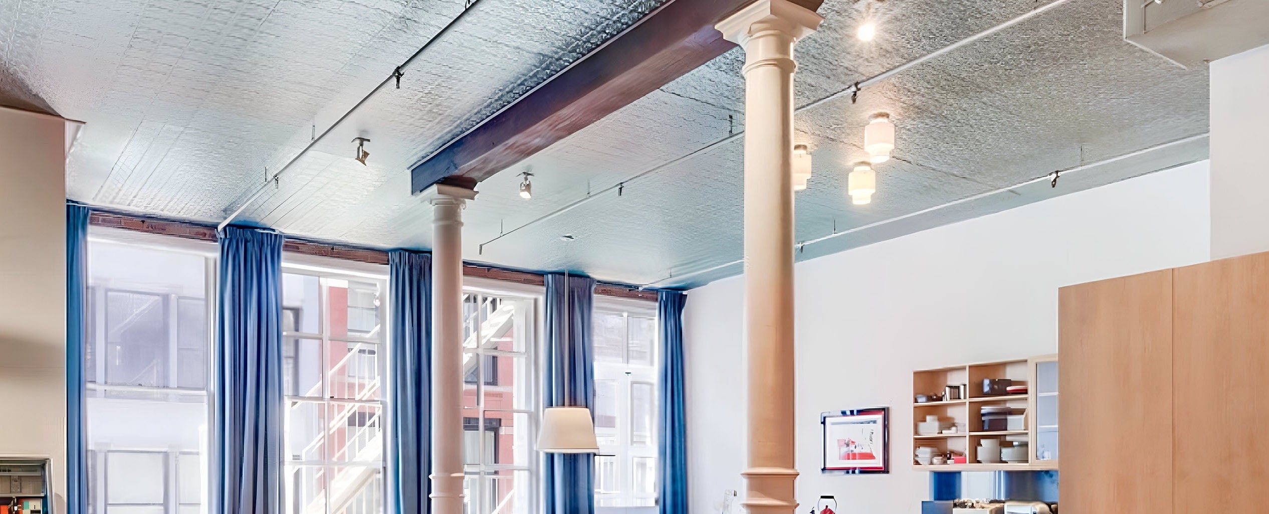 Modern office interior with large windows, blue curtains, and wooden furniture.