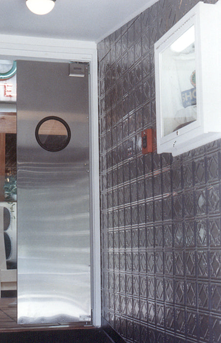 Glass door with decorative pattern in a room with tiled walls.