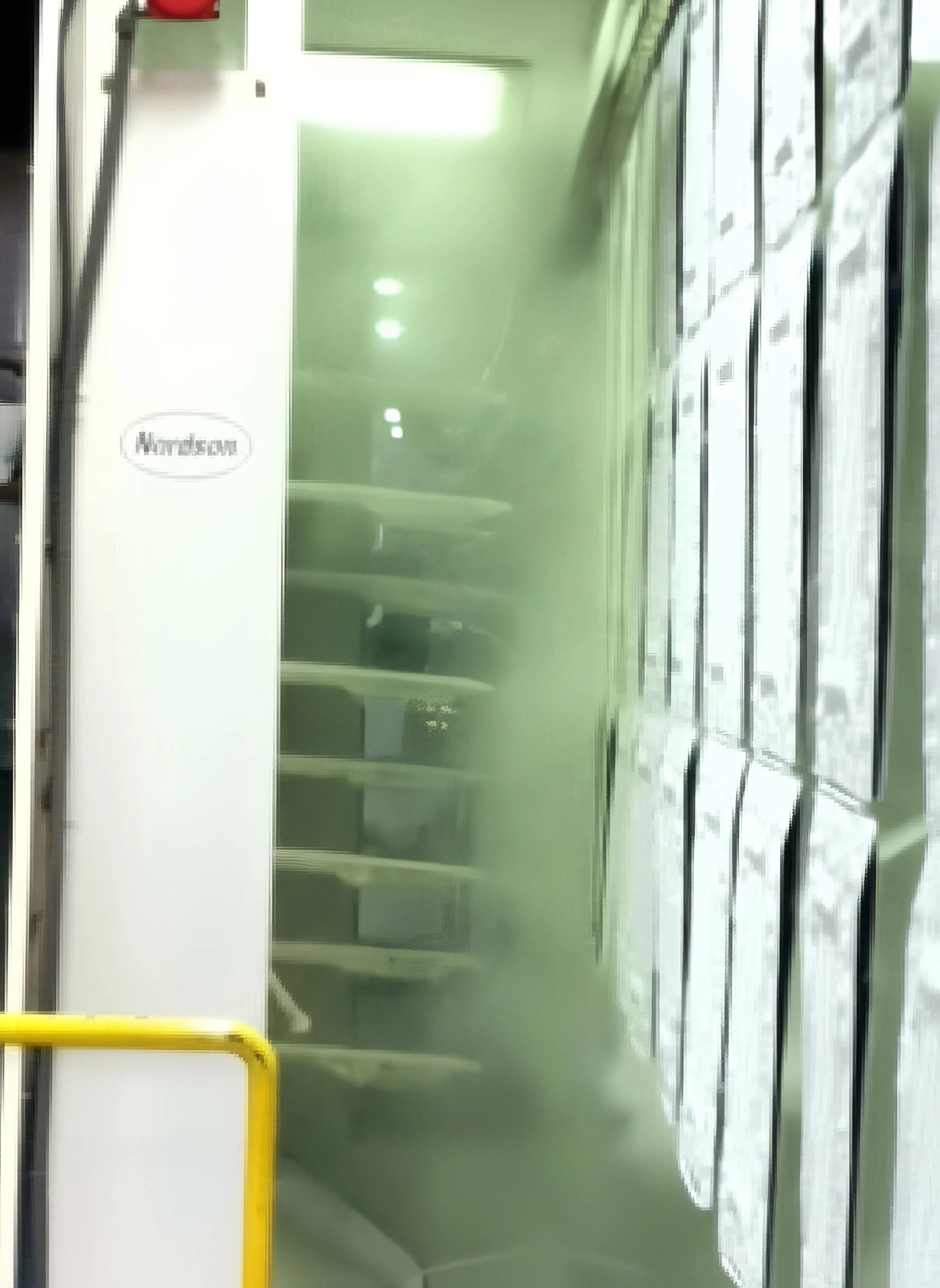 Nordson branded machine with a yellow handle in a room with shelves and cabinets.