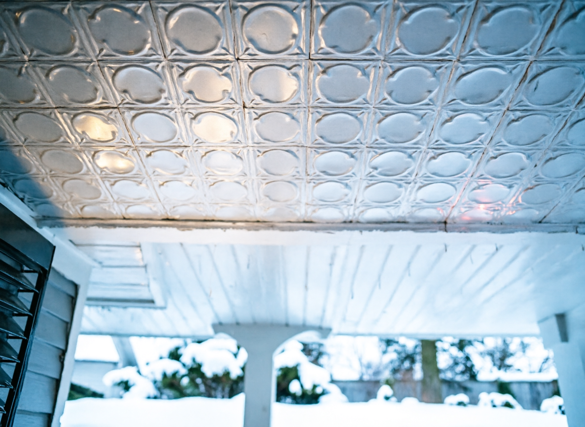 Ceiling with decorative tile pattern and snow-covered ground outside
