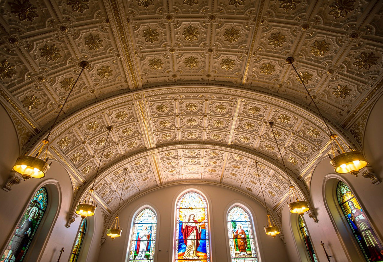 Arched ceiling with decorative patterns and stained glass windows in a church.