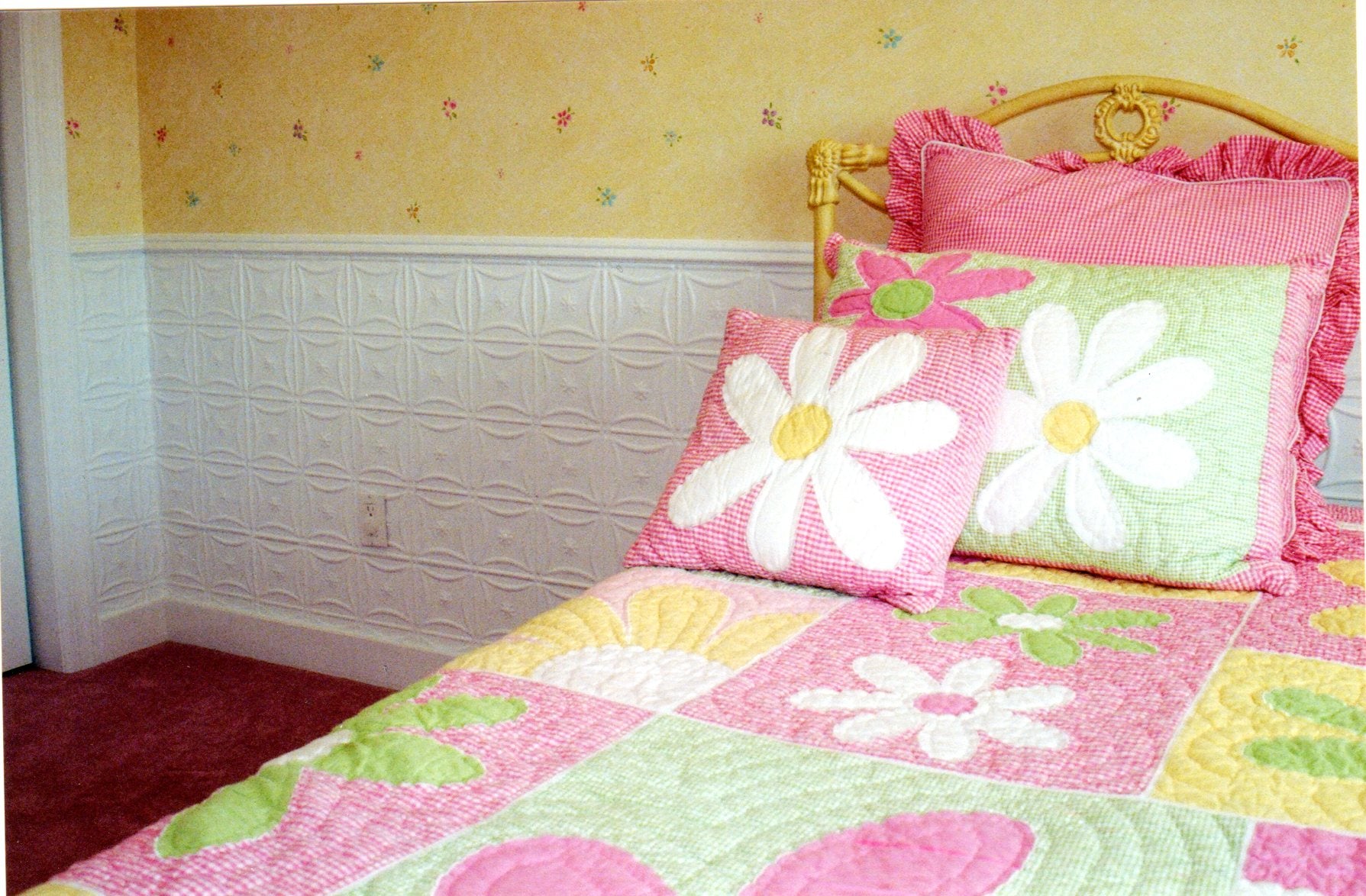 Children's bedroom with floral bedding and pillows on a bed.