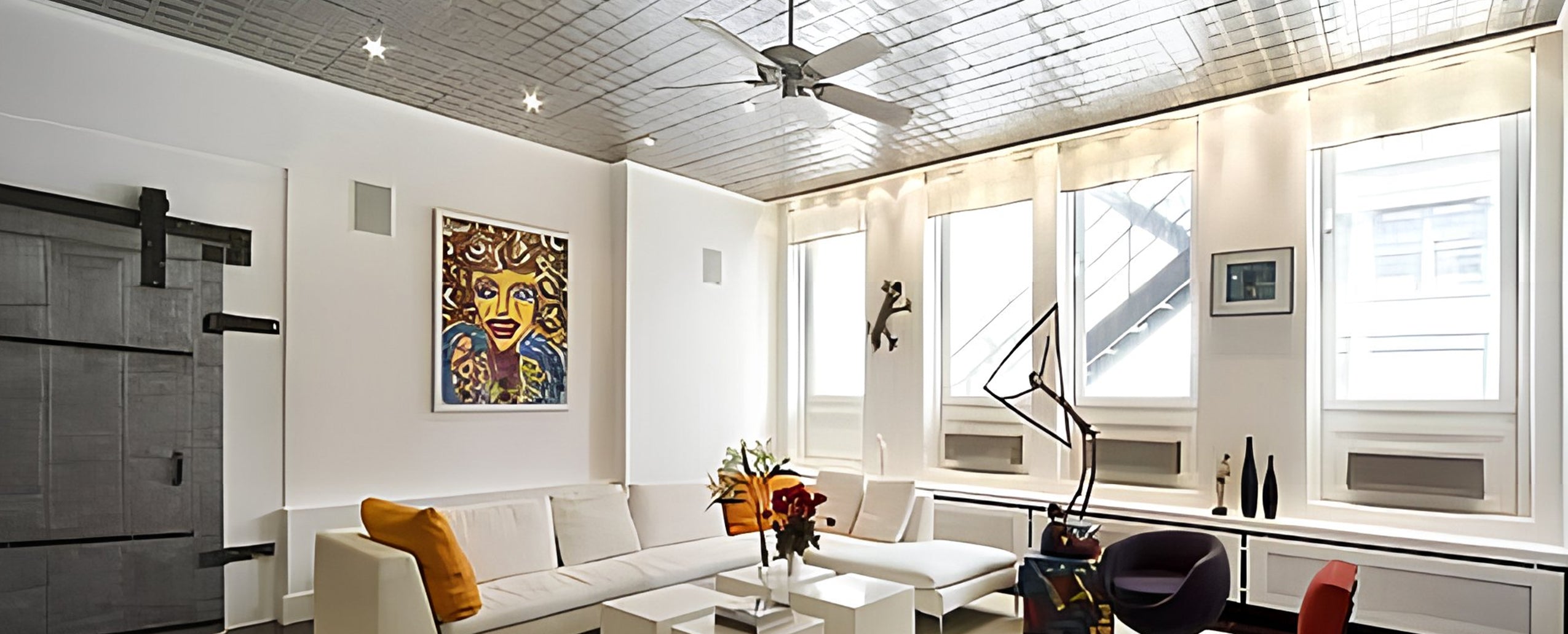 Modern living room with white walls, a ceiling fan, and decorative elements.