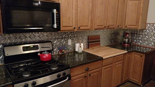 Kitchen with black stove, red pot, and wooden cabinets.