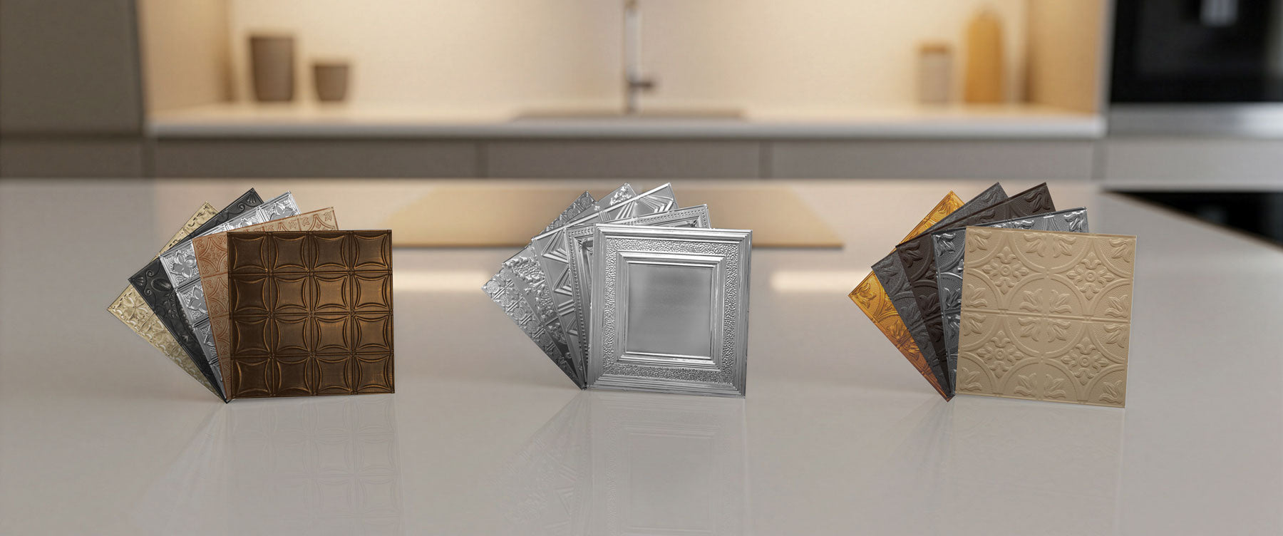 Collection of metallic sample tiles on a reflective surface with a blurred kitchen background.